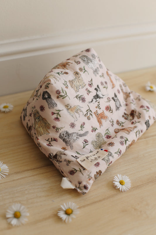 La Doucette coussin de lecture artisanal en Liberty of London imprimé chiens et fleurs rose poudré, vue de dessus, étiquette Des fils et des mots fabrication française, marguerites sur parquet bois