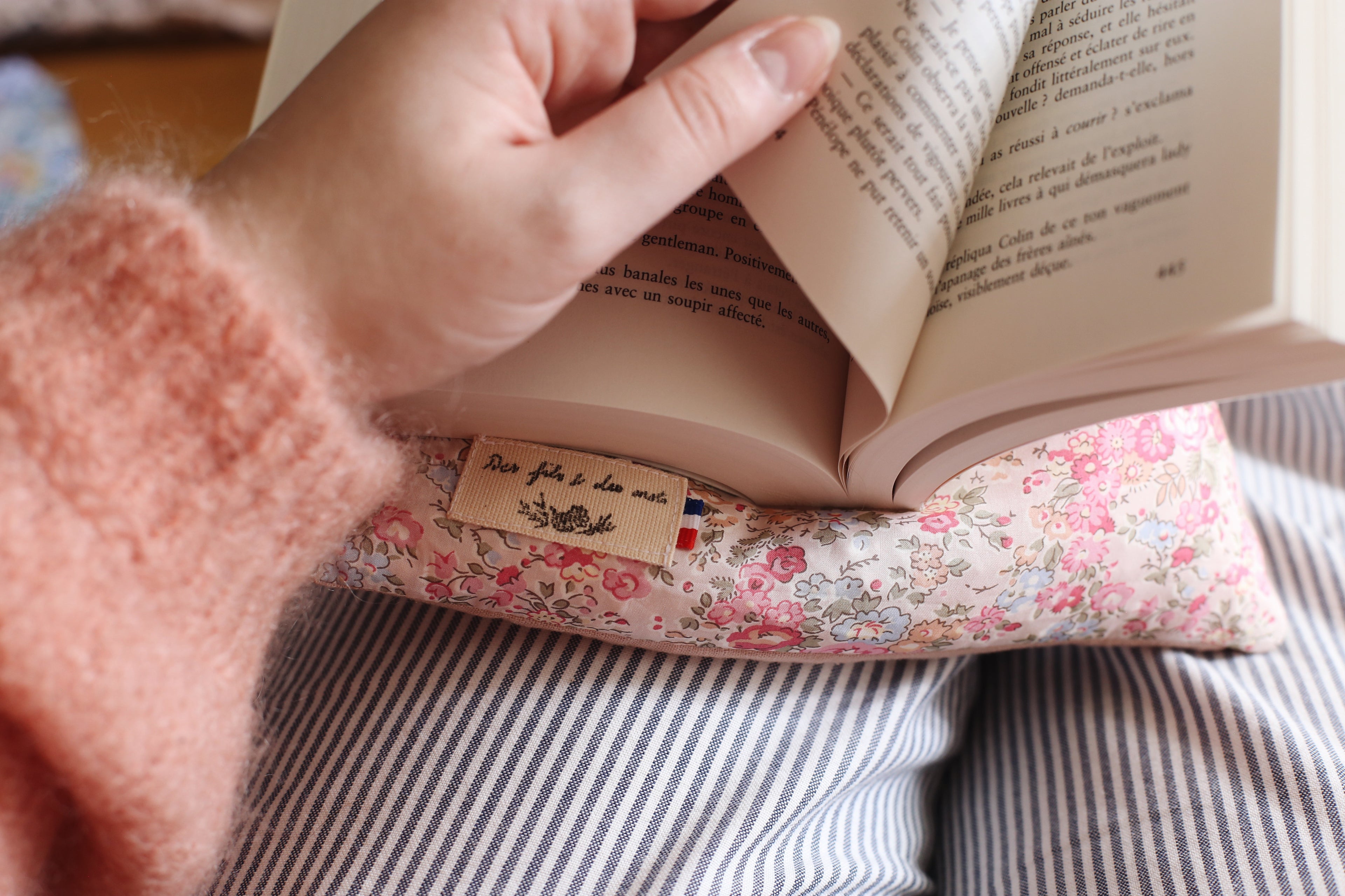 Coussin de lecture La Doucette Liberty of London fleuri en situation - livre ouvert tenu à la main, fabrication française - Des fils et des mots